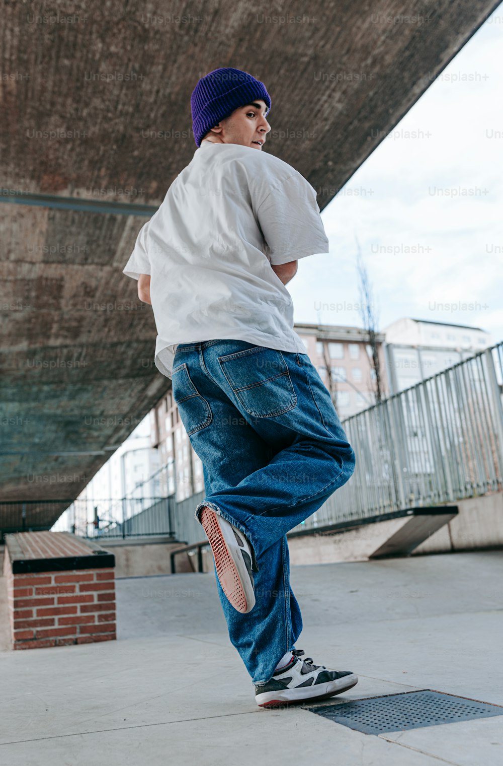 Ein junger Mann fährt auf einem Skateboard unter einer Brücke hindurch