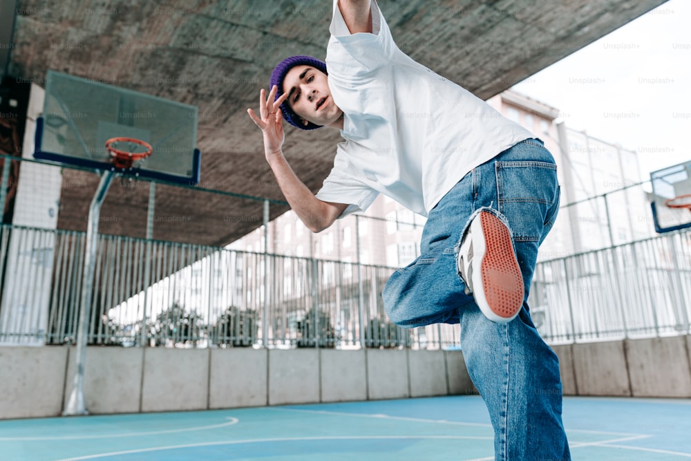 a man in white shirt and jeans playing basketball