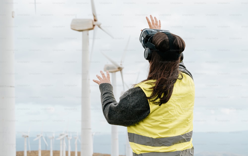 a woman in a yellow vest standing in front of wind turbines