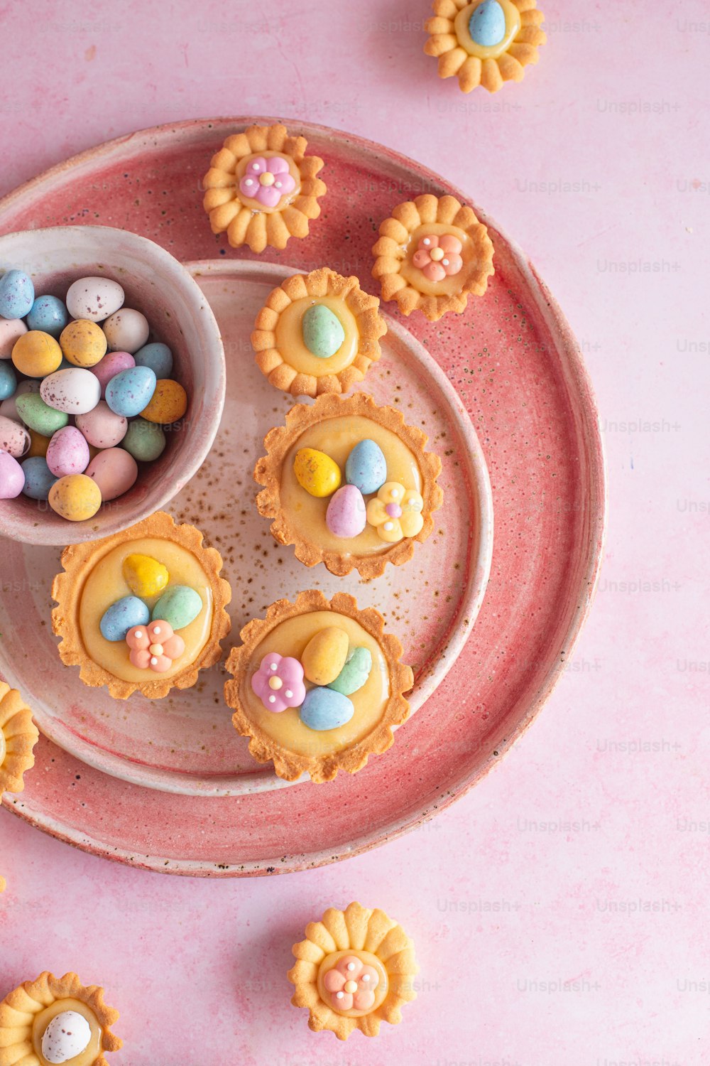 a pink plate topped with cupcakes covered in candy
