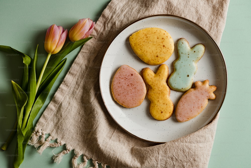 a white plate topped with cookies next to a pink tulip
