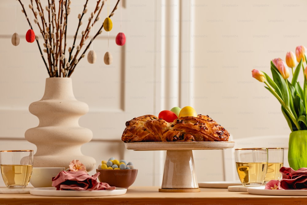 una mesa coronada con un pastel junto a un jarrón lleno de flores