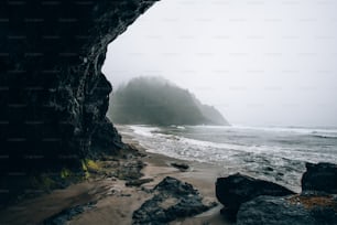 a beach with rocks and water on a foggy day