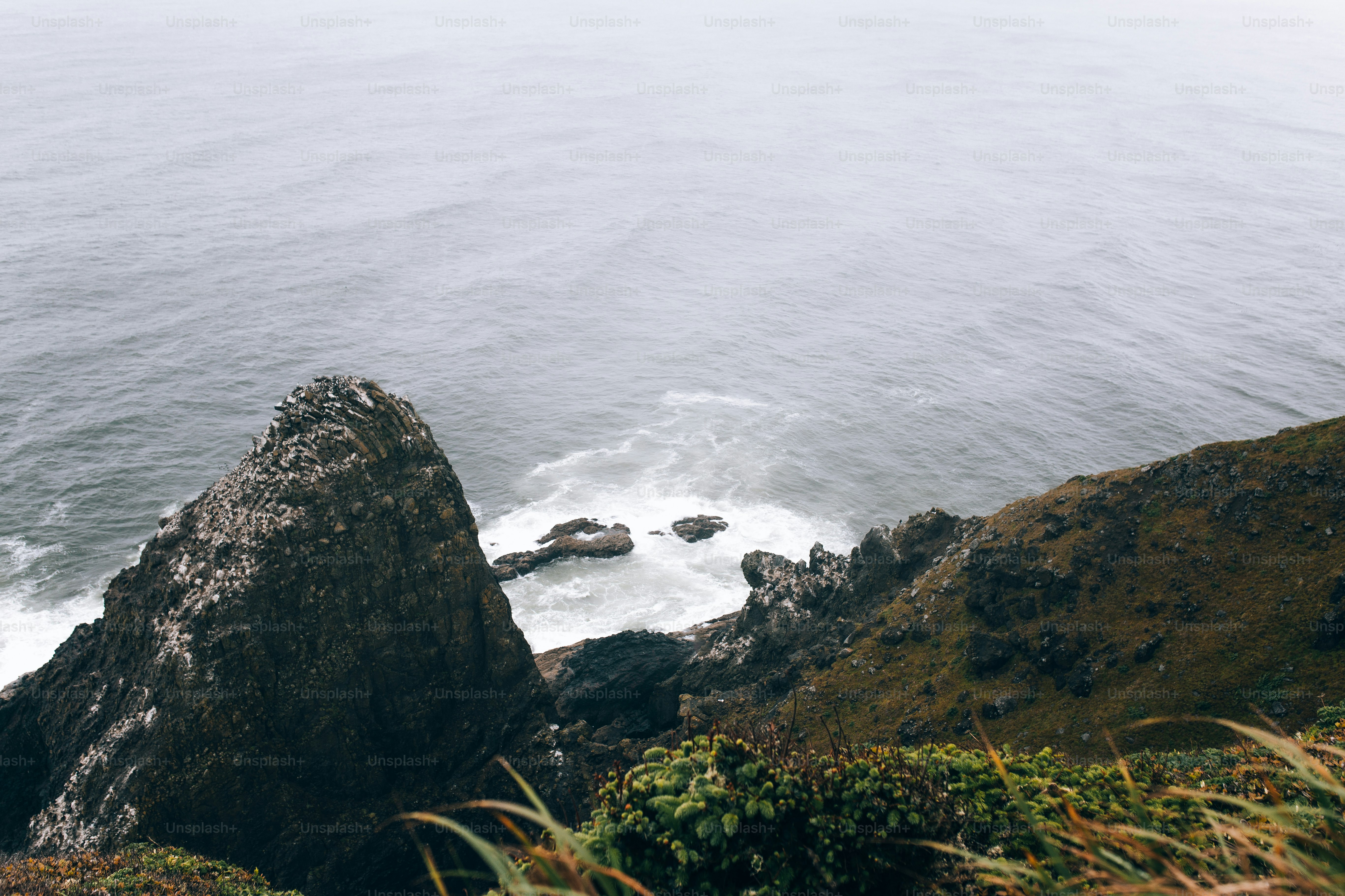 A couple of rocks sitting on top of a lush green hillside photo ...