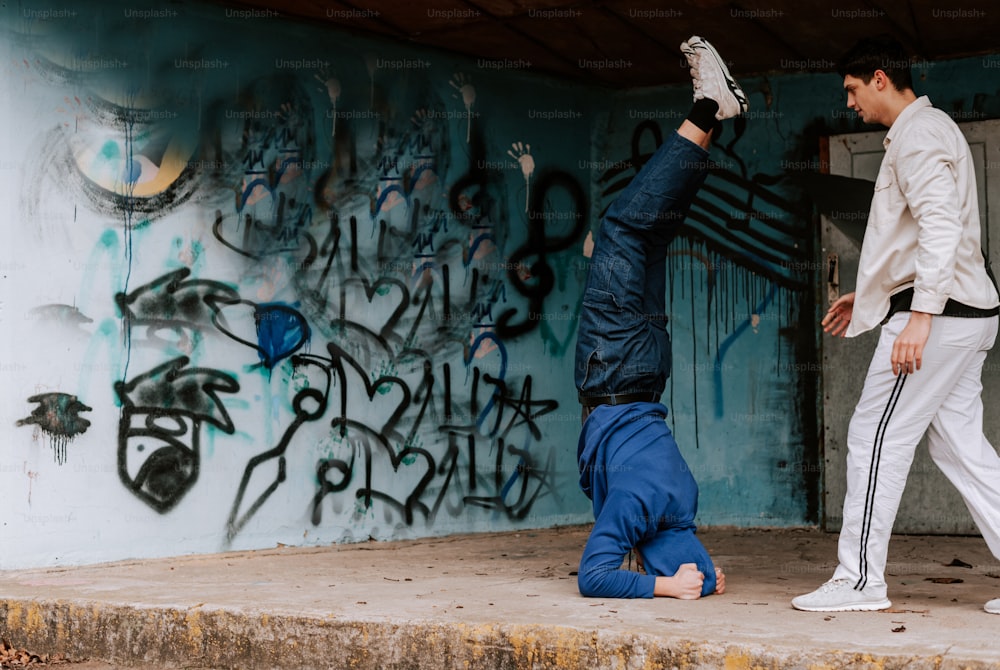 a man is doing a handstand in front of a graffiti covered wall