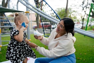 a woman holding a baby while sitting on a park bench