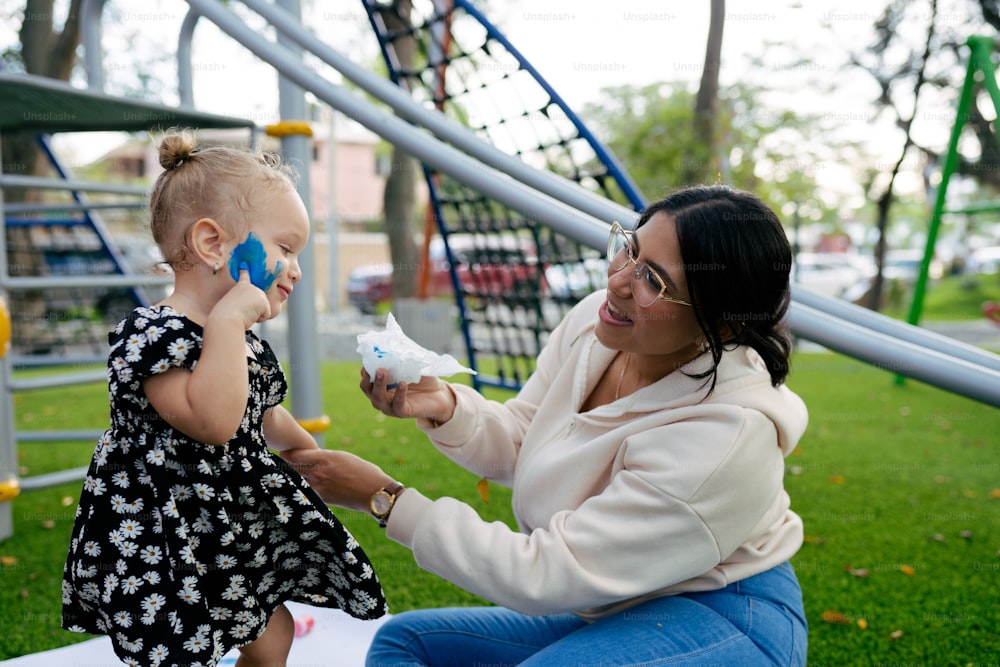a woman holding a baby while sitting on a park bench
