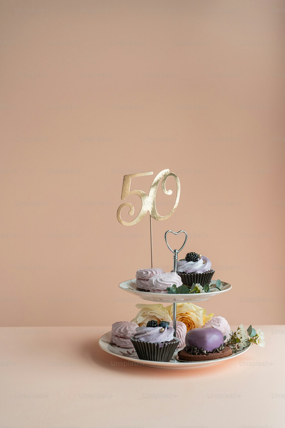 un plato de tres pisos con cupcakes y un pastel