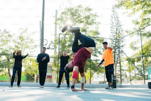 a man doing a handstand on a skateboard in front of a group