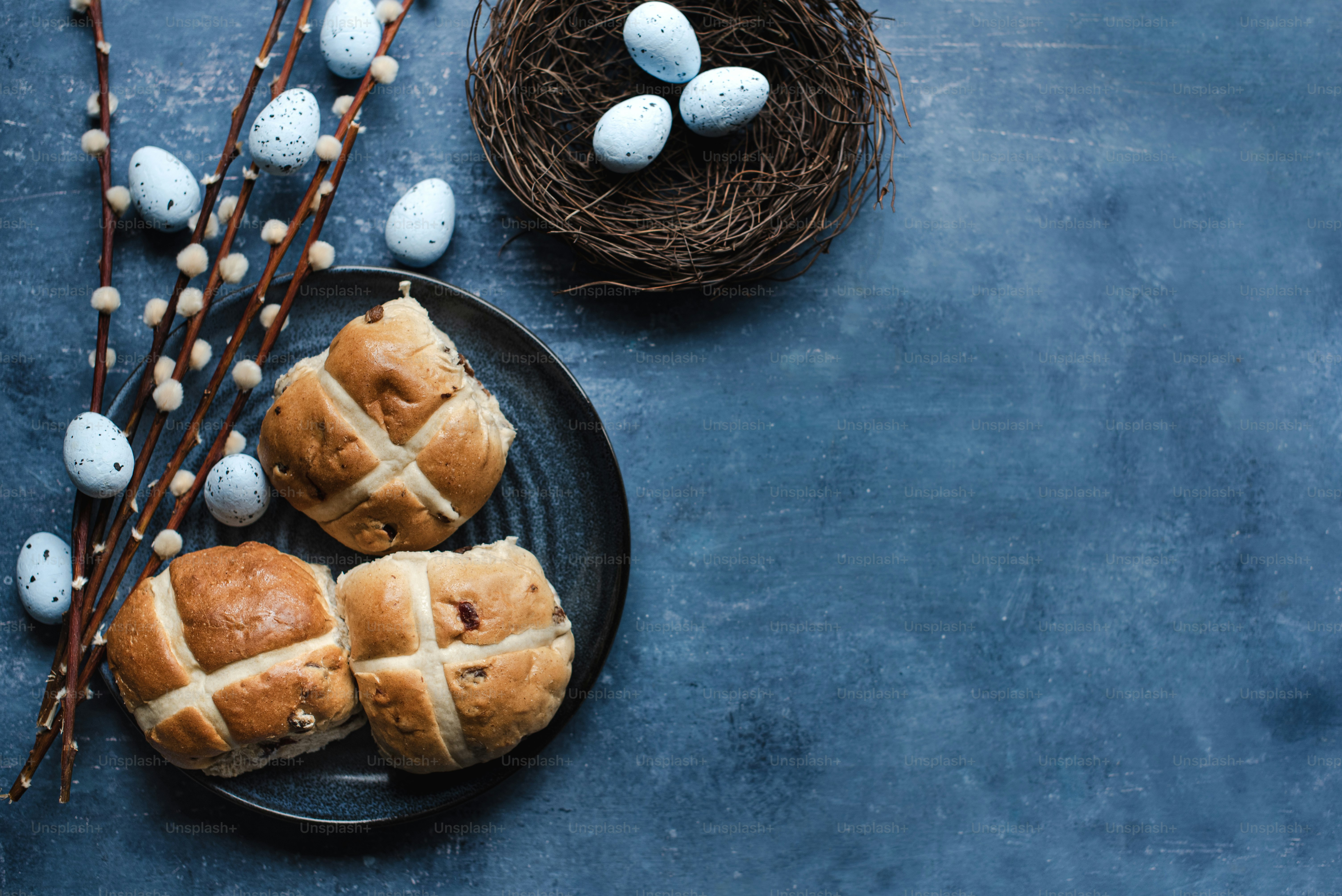 two hot cross buns on a plate next to a bird's nest