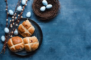 two hot cross buns on a plate next to a bird's nest
