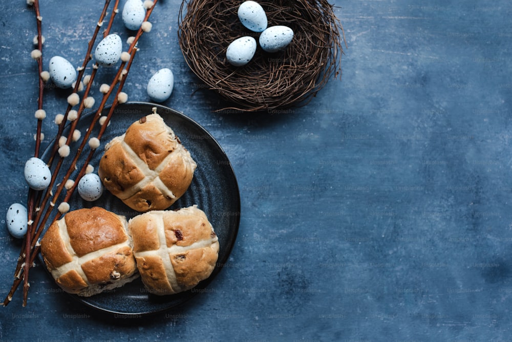 two hot cross buns on a plate next to a bird's nest