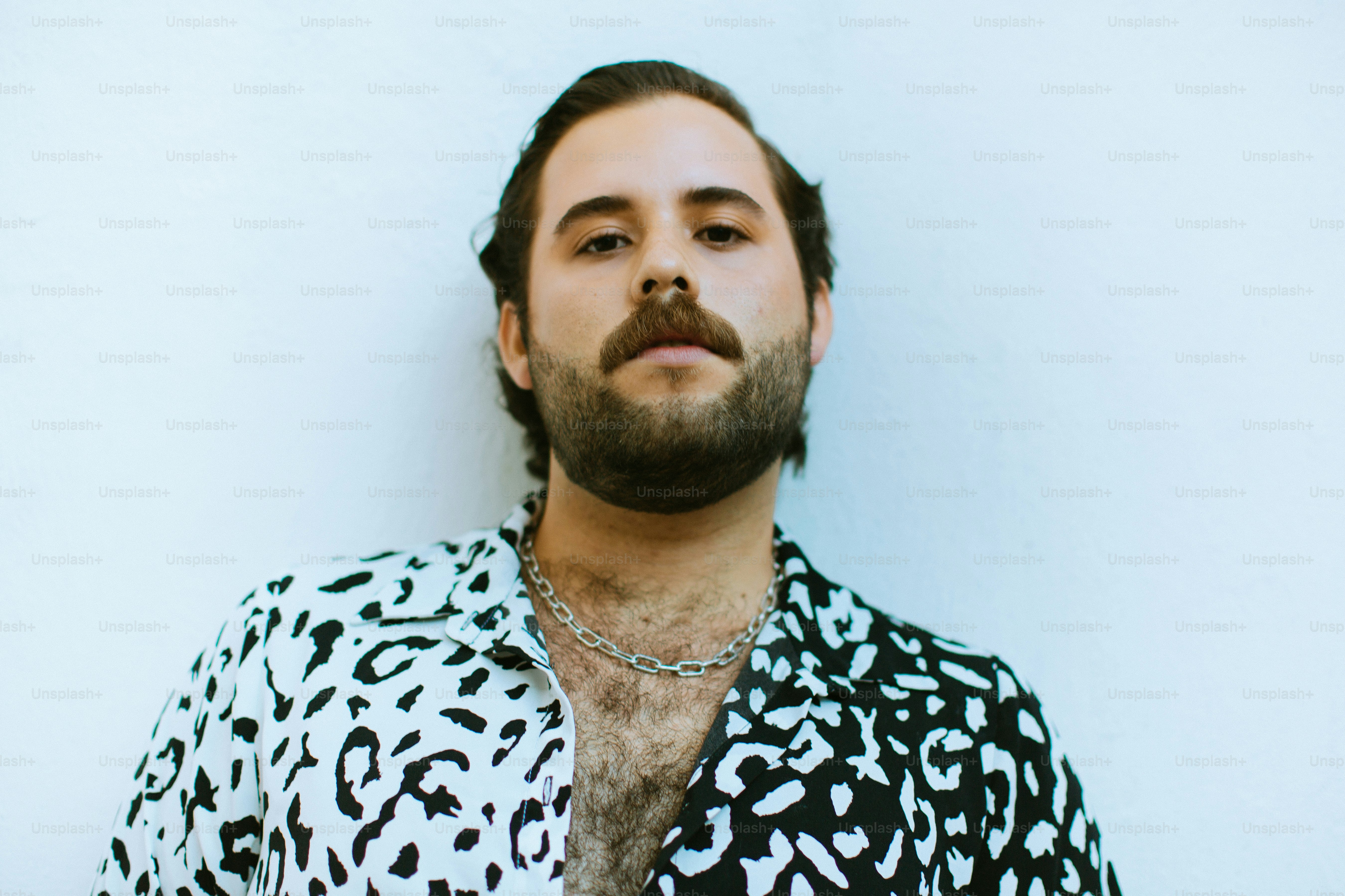 Man with beard and patterned shirt against white wall