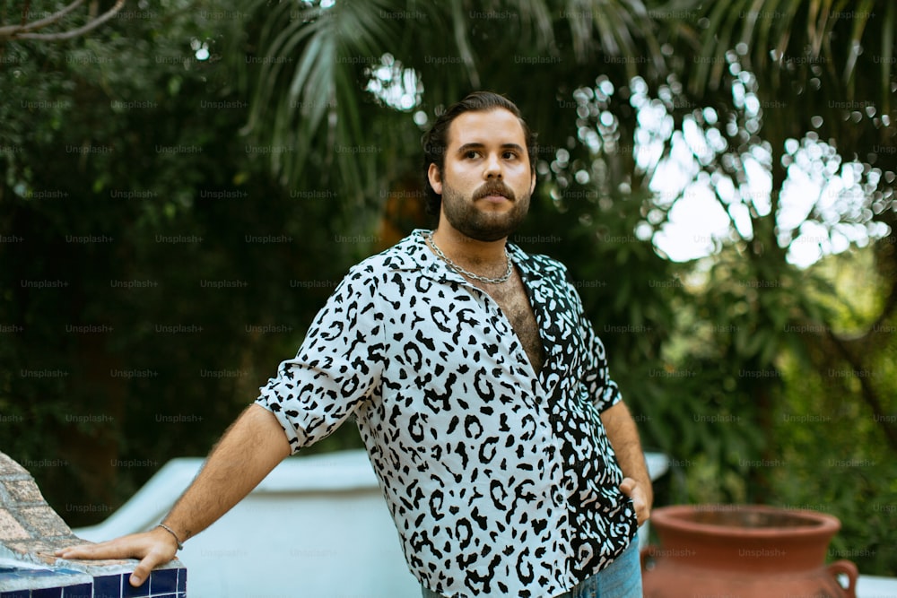 a man in a leopard print shirt leaning against a wall