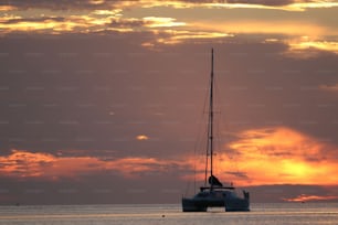 a sailboat in the ocean at sunset