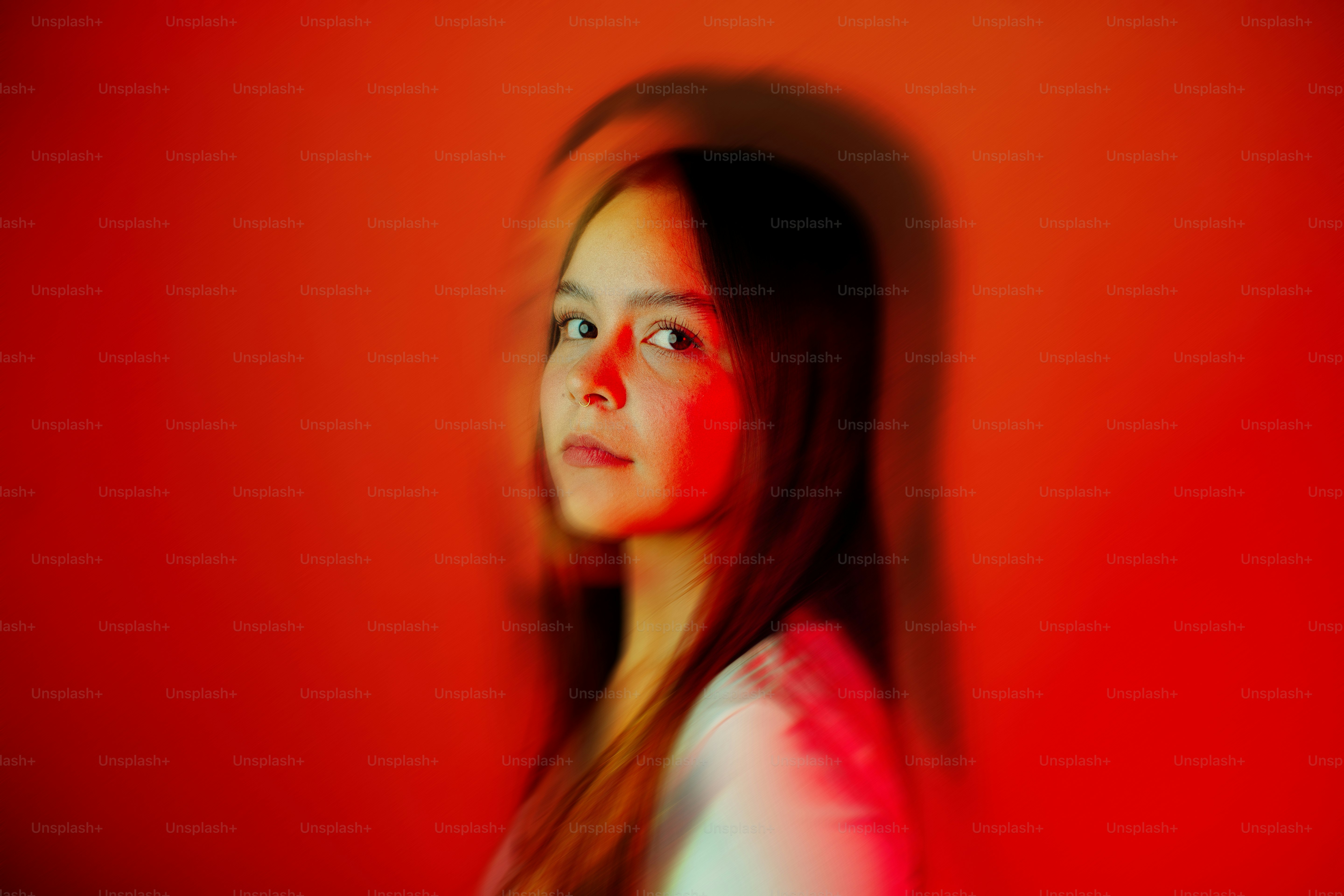 A girl with long hair standing in front of a red wall photo – Portrait ...
