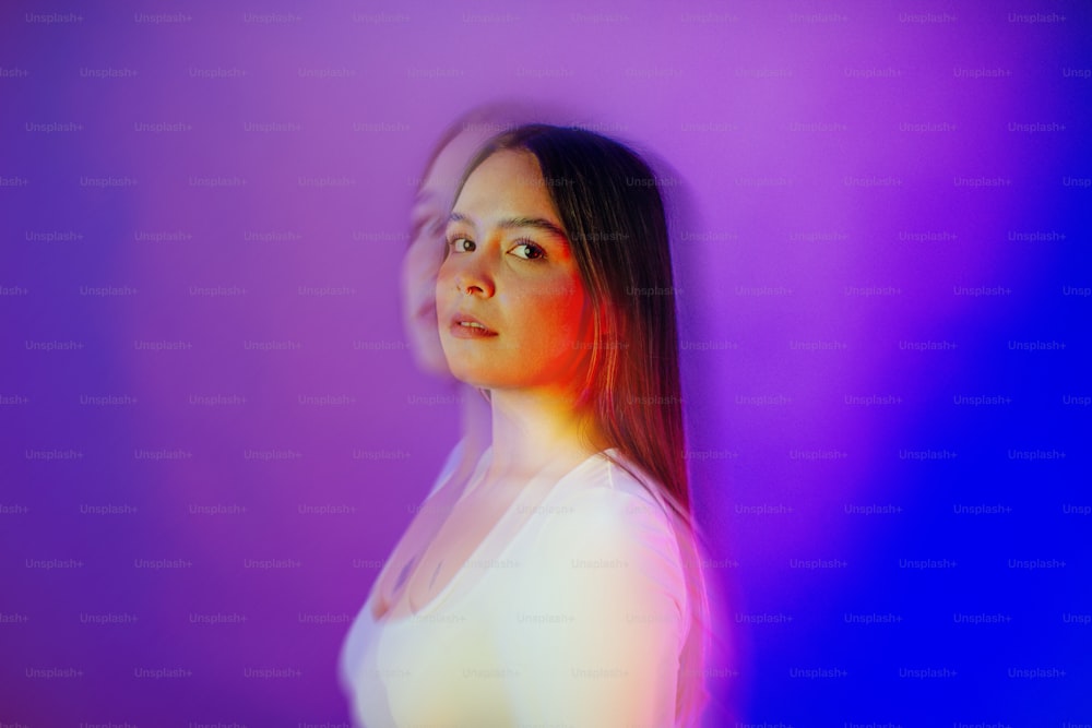 une femme en chemise blanche debout devant un fond violet