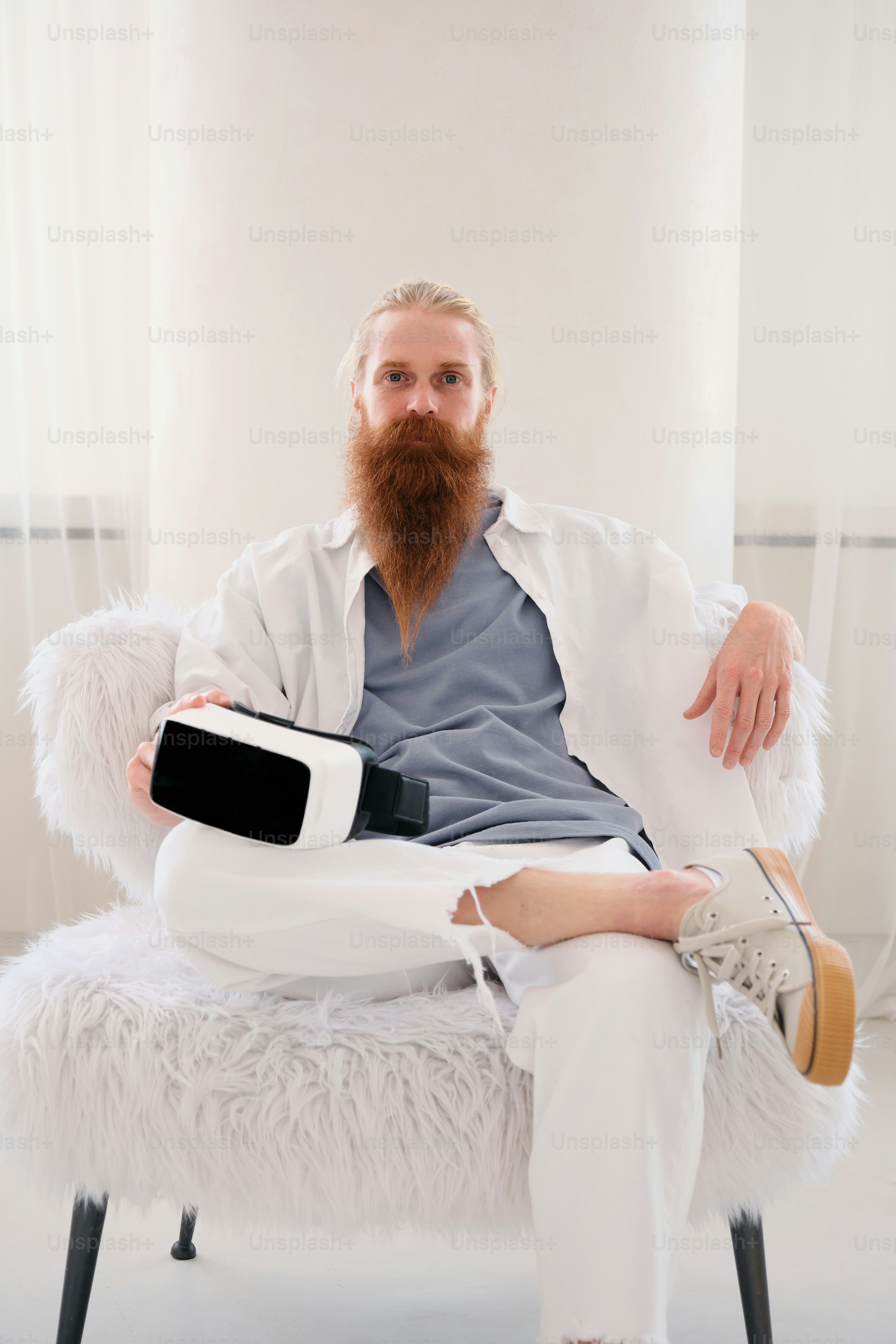 a man with a beard sitting on a white chair