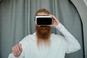 a man with a long beard is holding a virtual device up to his face