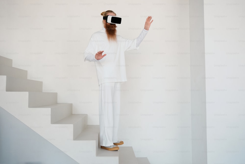 um homem com uma longa barba vestindo uma roupa branca em pé em um conjunto de escadas