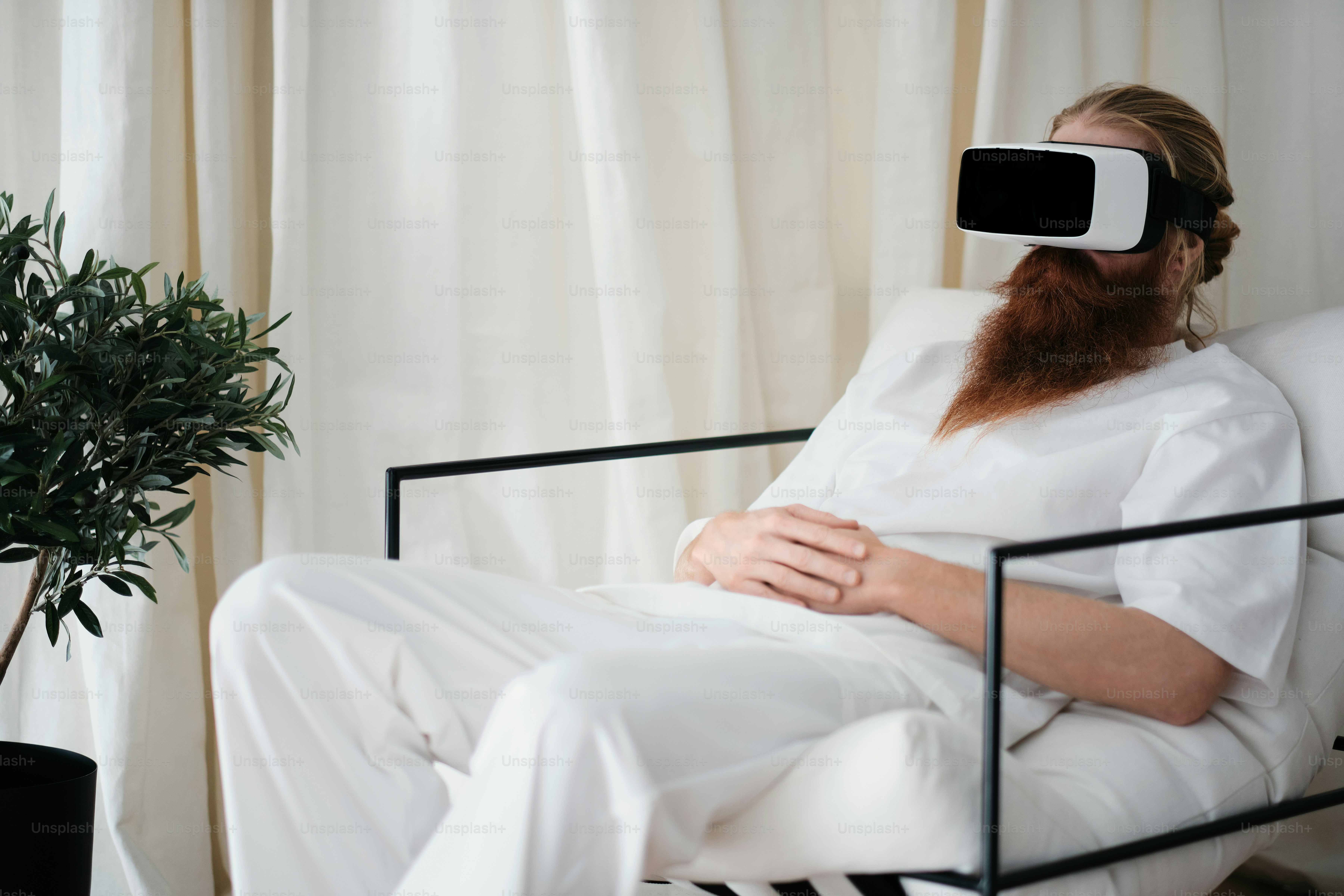 A man sitting in a chair wearing a virtual reality headset photo – Man ...