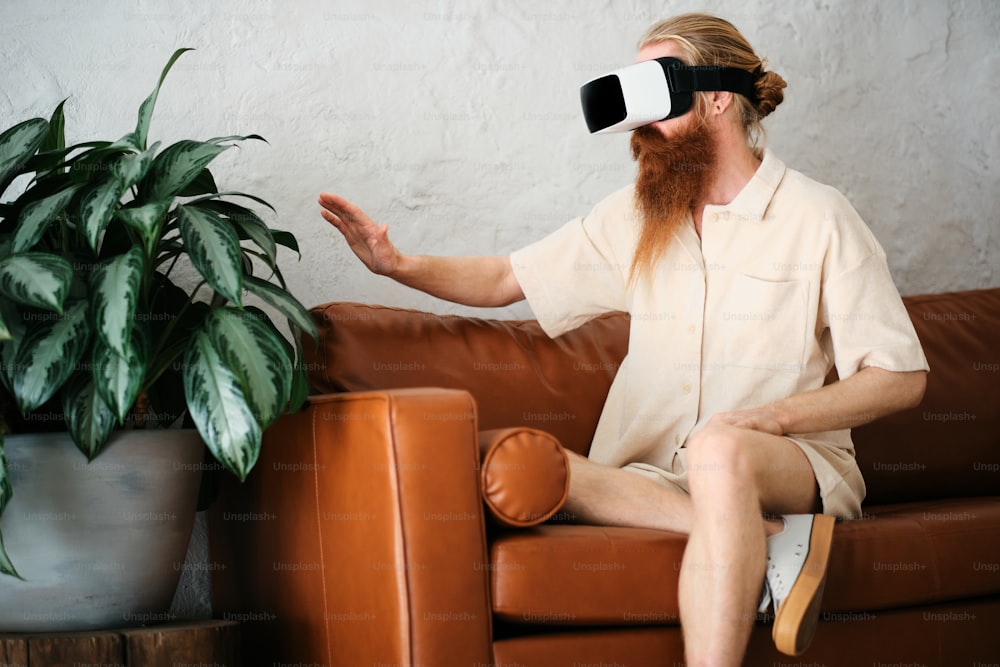 um homem sentado em um sofá usando um par de óculos virtuais