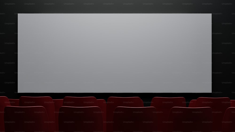 a large screen in a dark room with red chairs