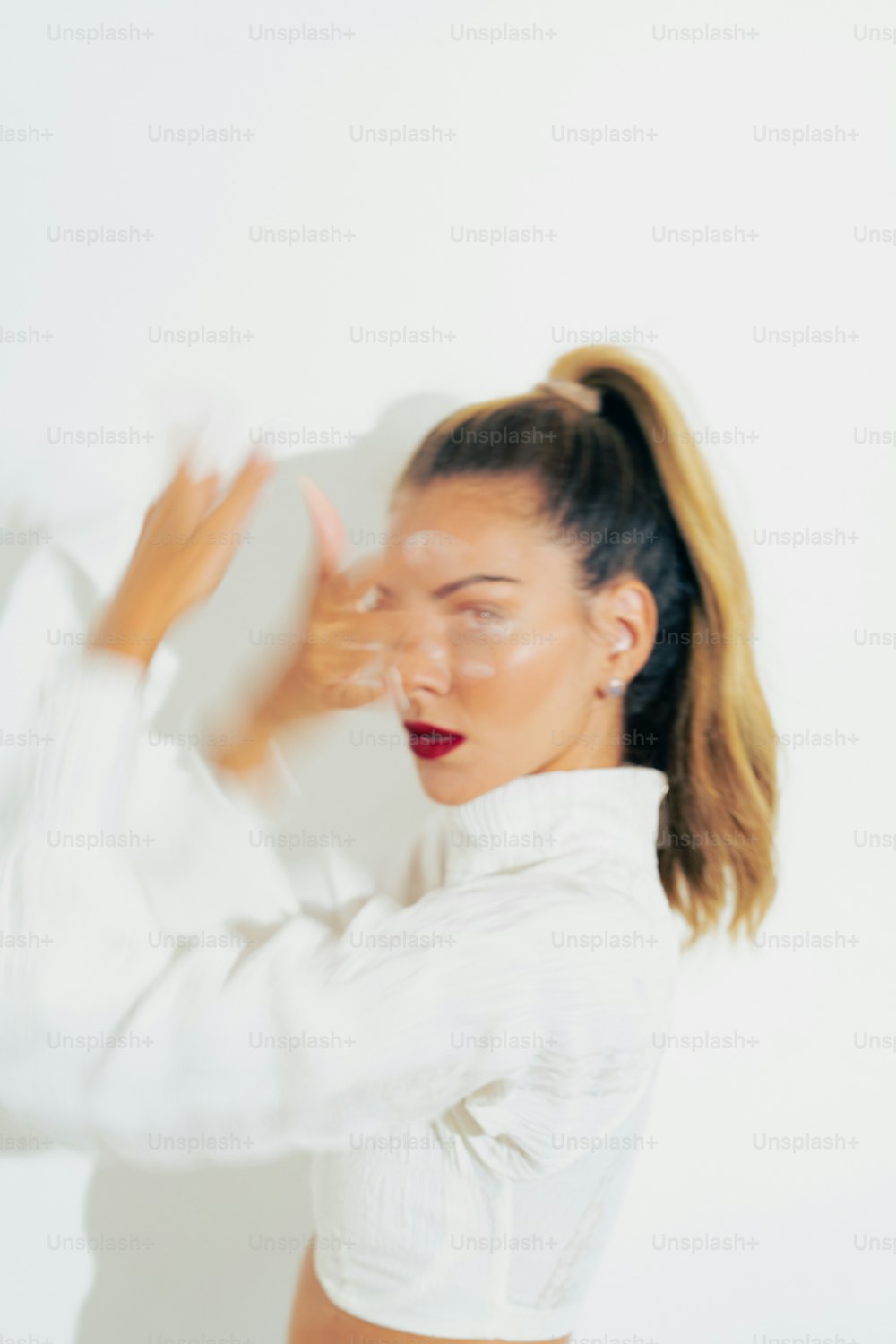 a woman in a white shirt is holding her hair in a ponytail