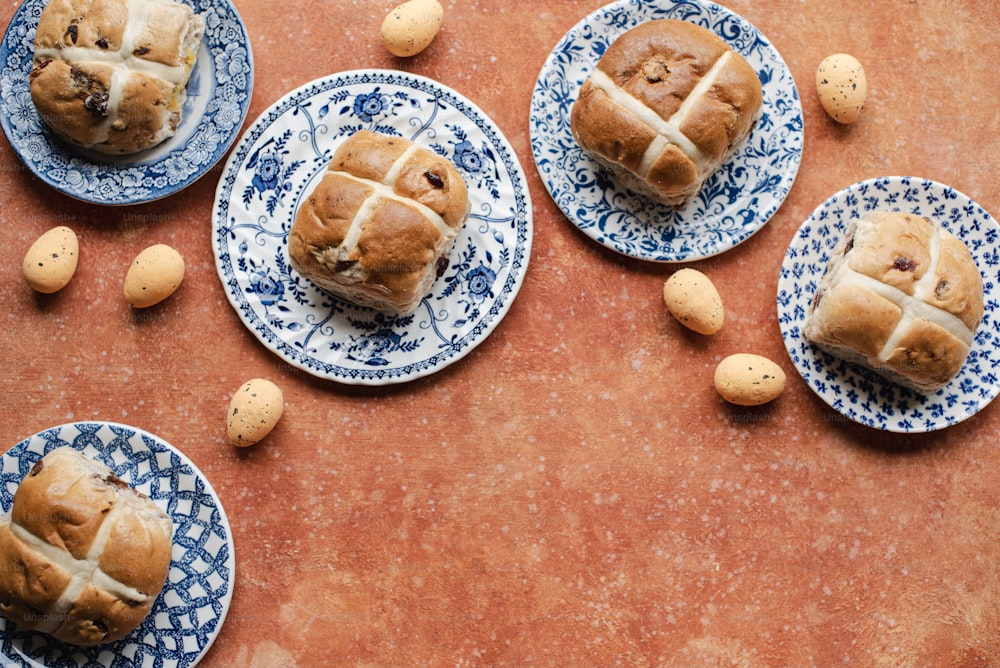 a table topped with blue and white plates filled with hot cross buns