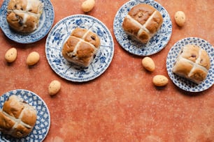 a table topped with blue and white plates filled with hot cross buns