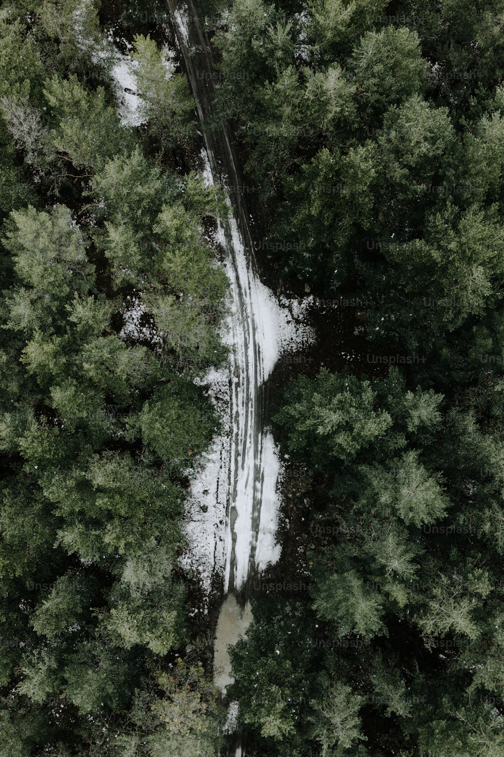 an aerial view of a snow covered road in the woods