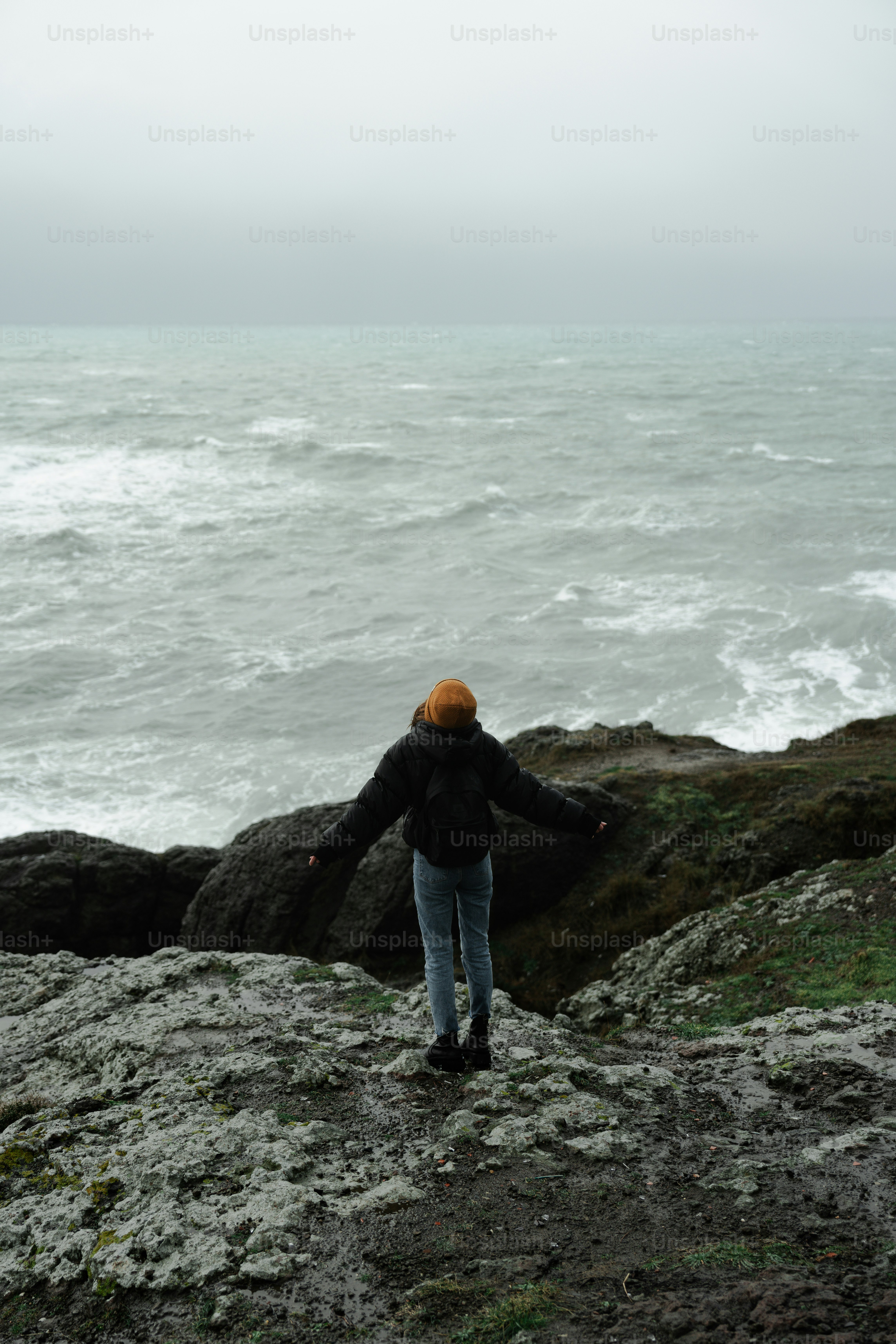 a person standing on top of a rock near the ocean