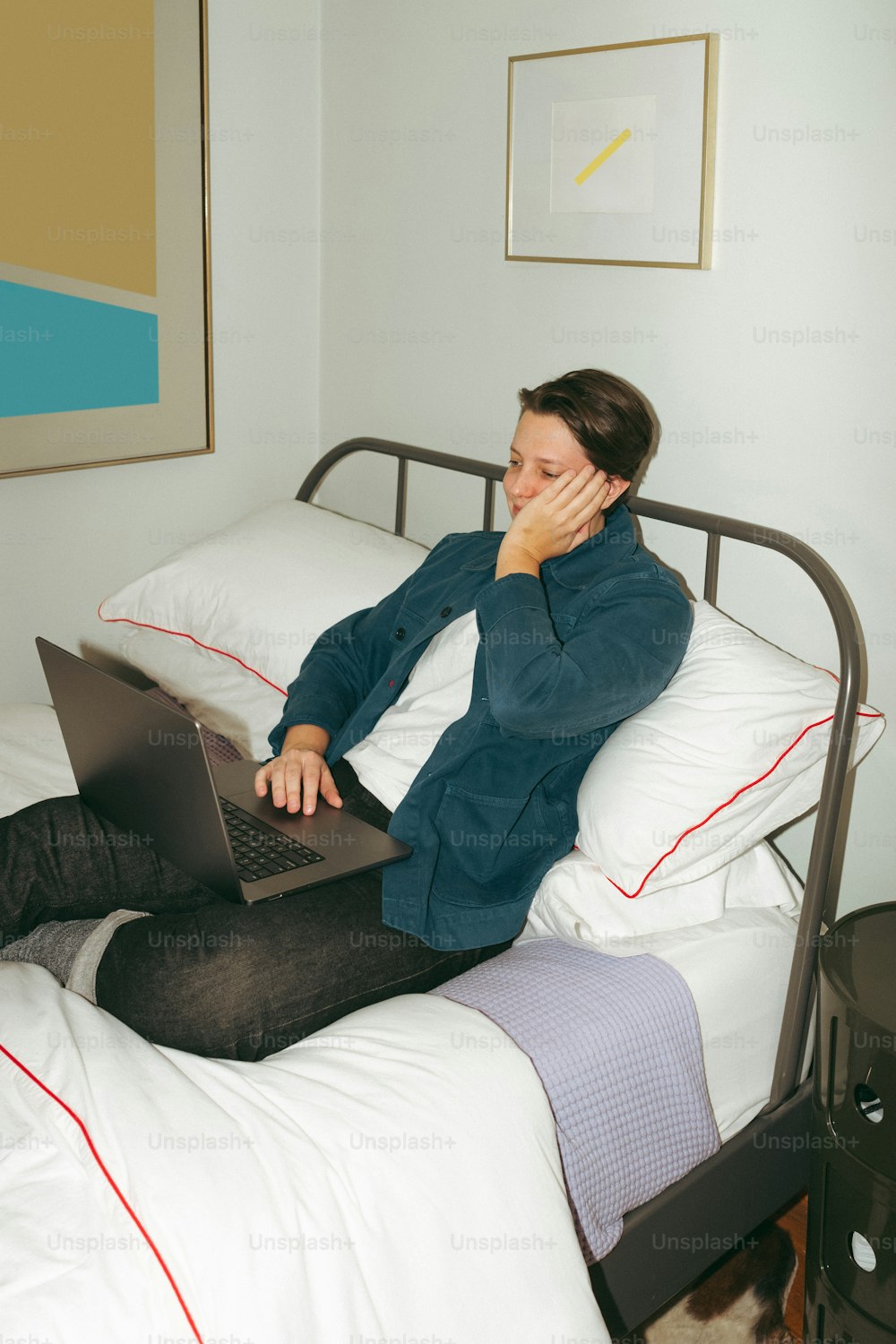 una mujer sentada en una cama usando una computadora portátil