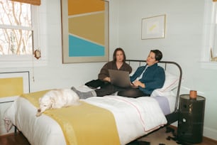 a couple of women sitting on top of a bed