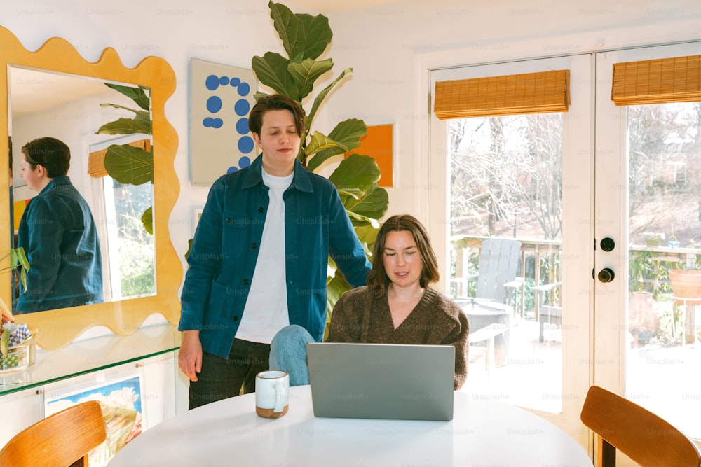 a man and a woman standing in front of a laptop