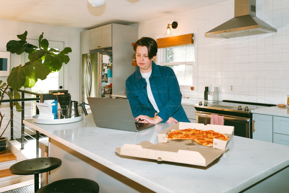 une femme assise à un comptoir de cuisine à l’aide d’un ordinateur portable
