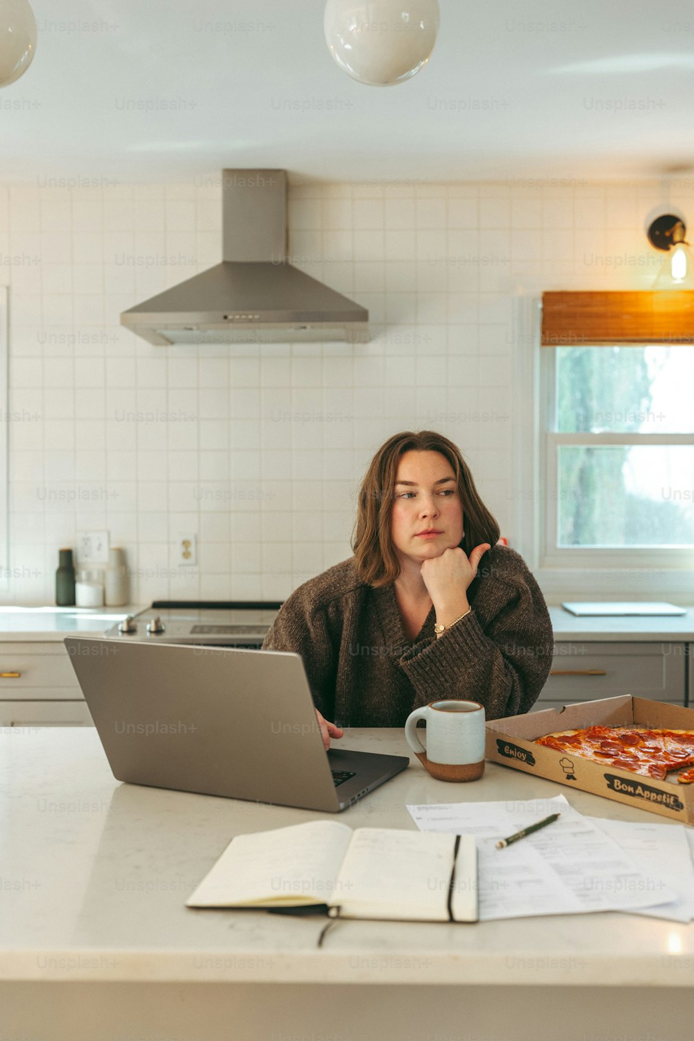 une femme assise à une table de cuisine avec un ordinateur portable