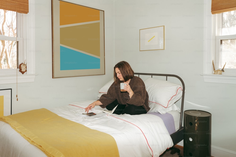una donna seduta su un letto con in mano un telecomando