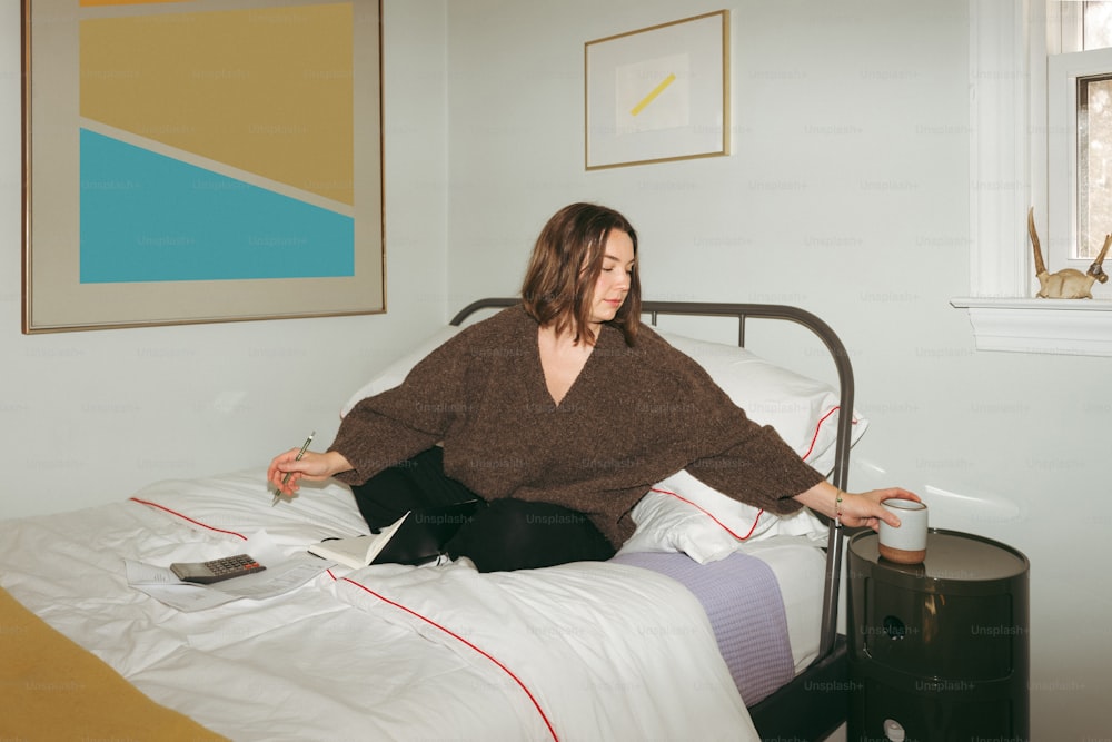 eine Frau, die auf einem Bett in einem Zimmer sitzt