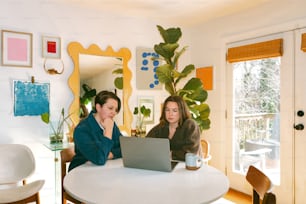 Dos mujeres sentadas en una mesa con un ordenador portátil