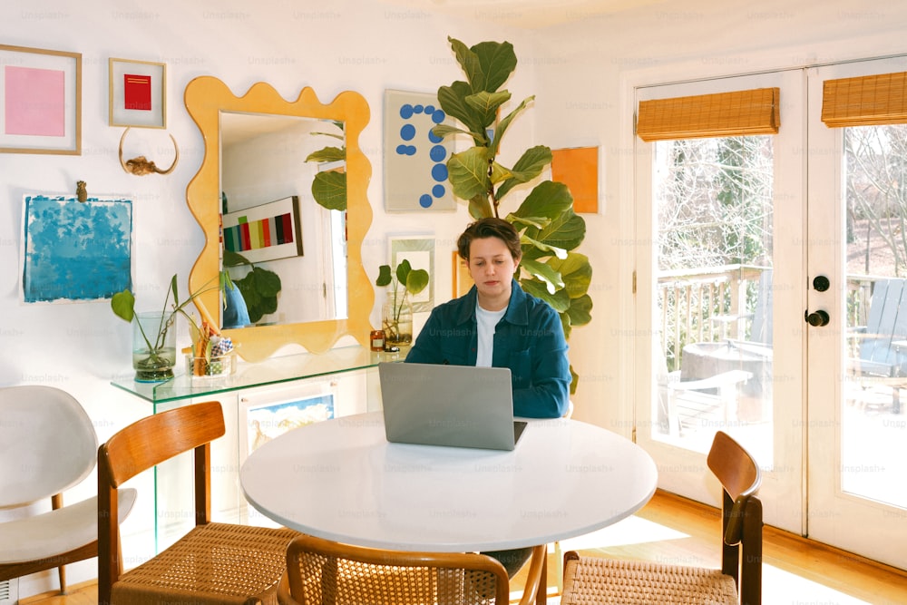 a woman sitting at a table with a laptop