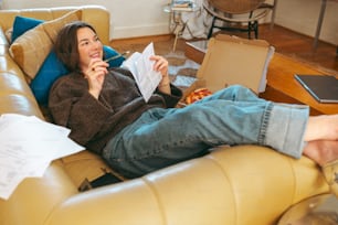 uma mulher sentada em um sofá comendo uma fatia de pizza