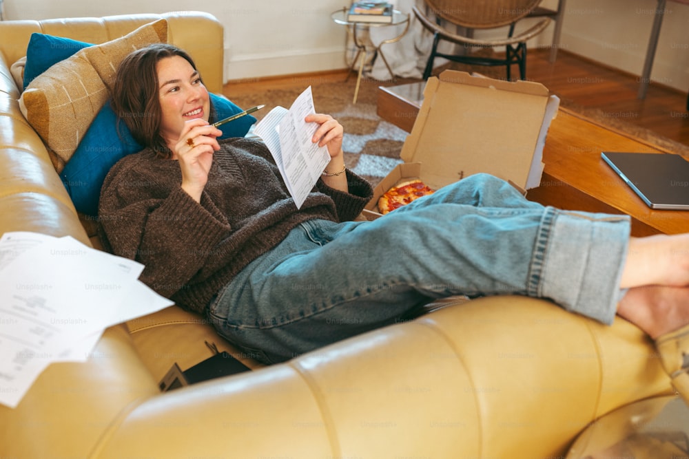 a woman sitting on a couch eating a slice of pizza
