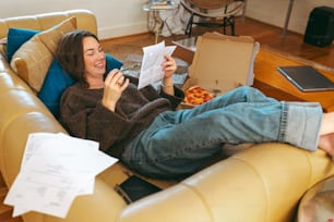 una mujer sentada en un sofá leyendo un pedazo de papel