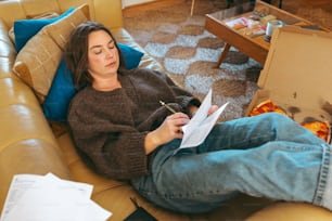 a woman sitting on a couch reading a piece of paper