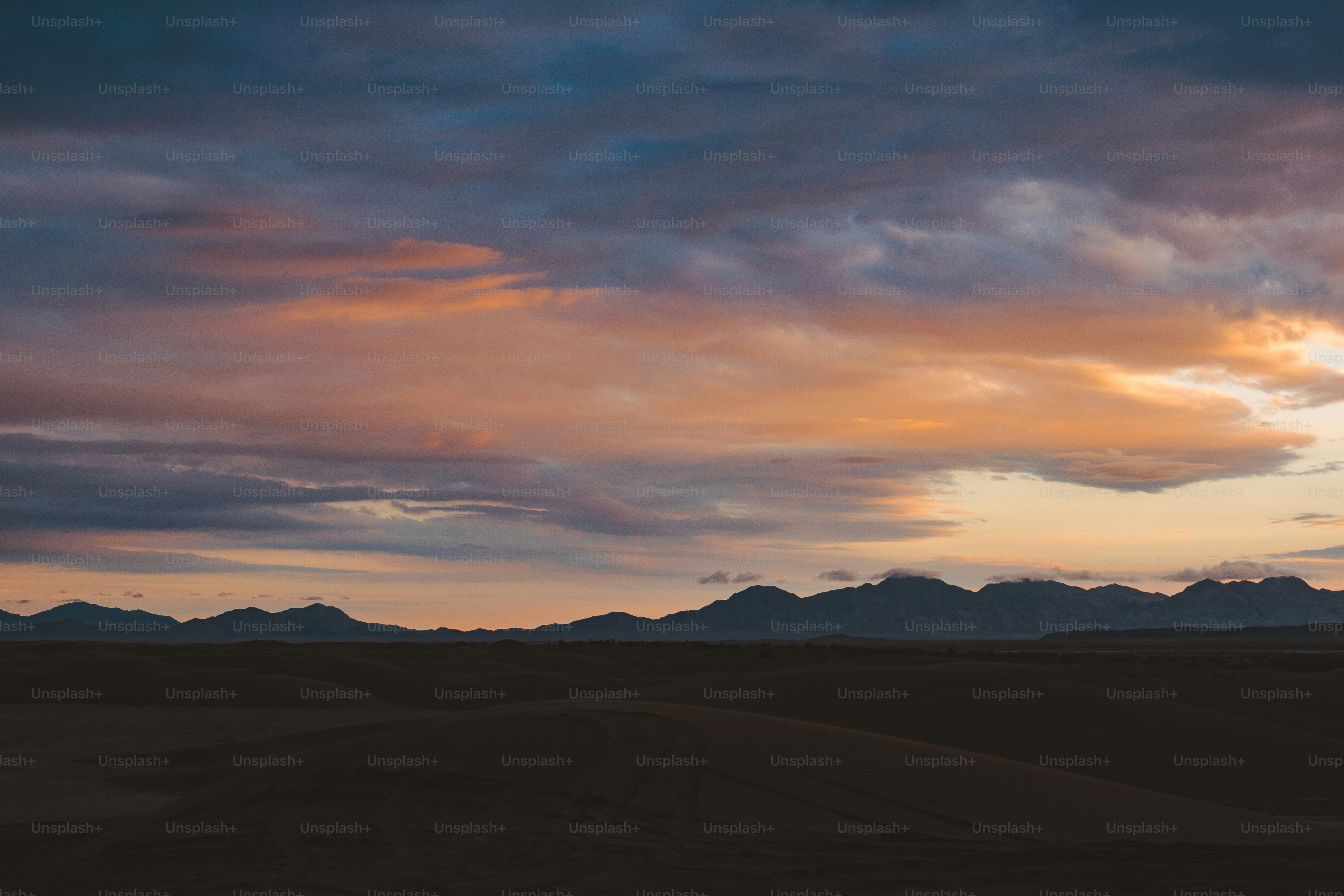a sunset with clouds and mountains in the background