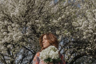 une femme tenant un bouquet de fleurs blanches