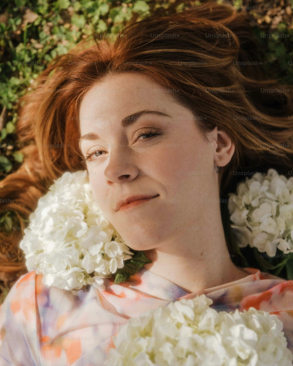 a woman laying down with flowers in her hair