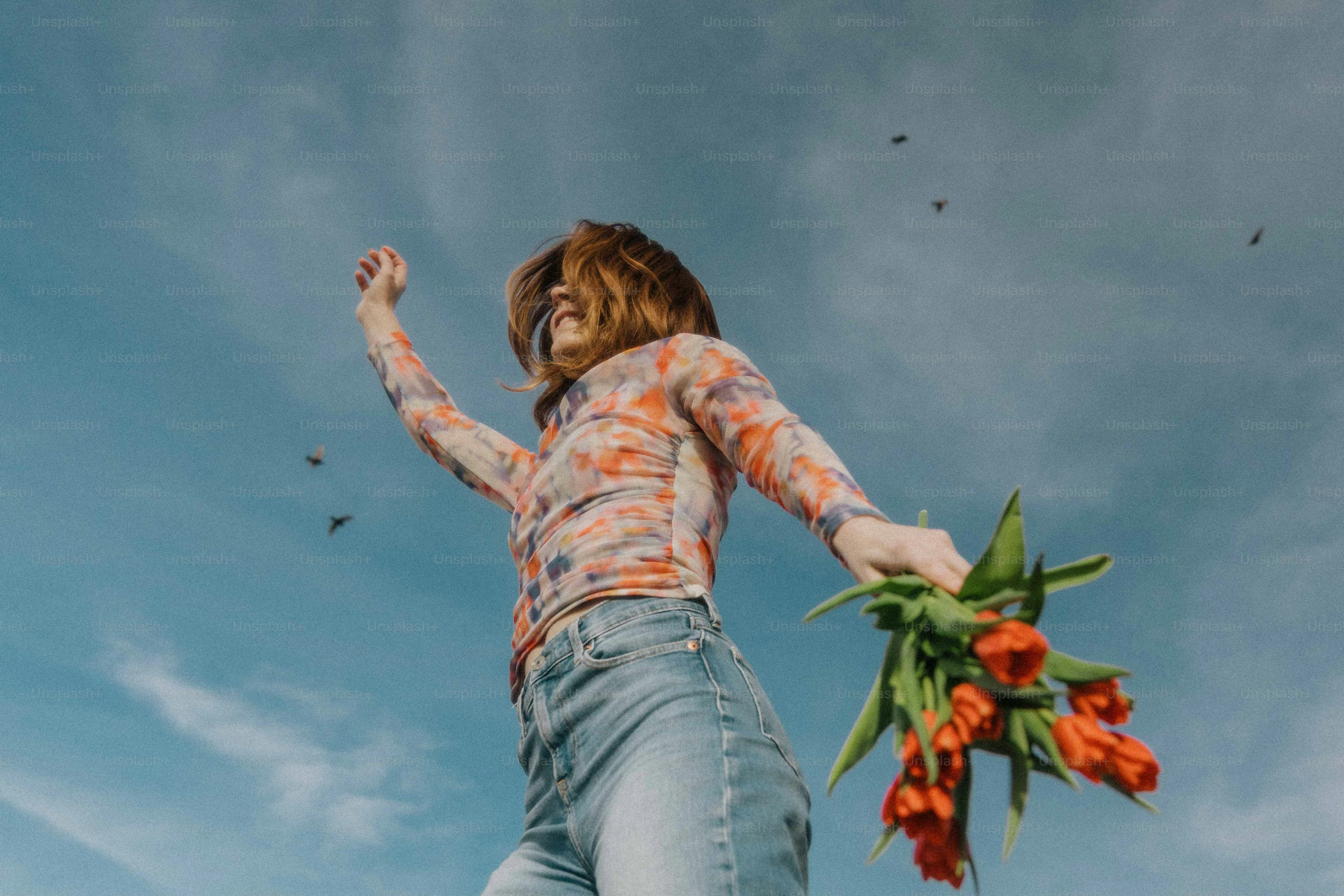 a woman holding a bunch of flowers up in the air