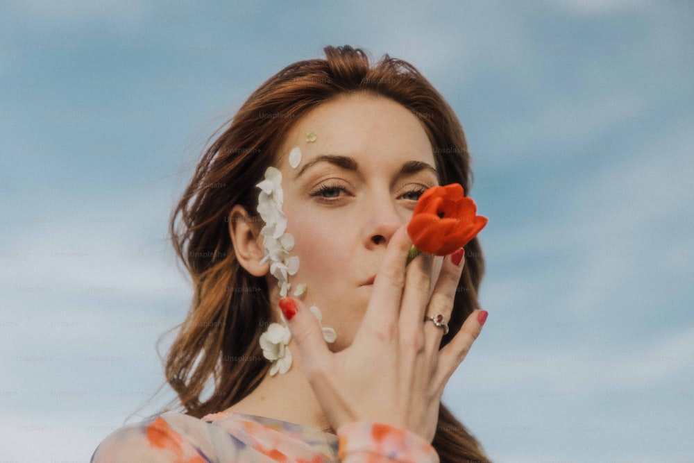 une femme tenant une fleur devant son visage